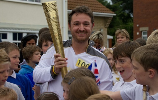 THE STAR'S THE TORCH: A proud torchbearer who is mobbed by children who are rightly more bothered about the torch than the man holding it (Claire Wiggins)  